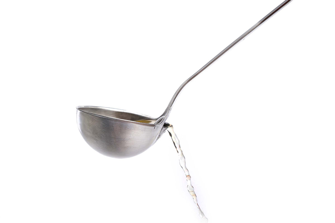 Side view of the fat skimming ladle showing clear broth pouring out the rear spout